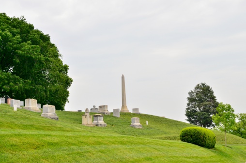 An obelisk stands at the top of a hill looking over the other tombstones in the Arlington National Cemetery on a rainy day. It seems more than a little ironic to have to display rank in this hallowed ground but whoever is buried there probably didn't have much to say about it