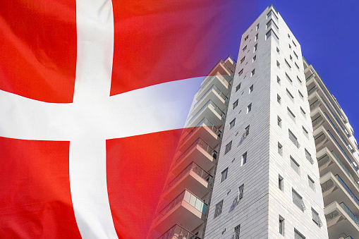 Modern residential building on background of flag Denmark. New apartment building on background of flag Denmark. Realty concept and home buying or new apartment in Denmark