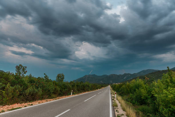 Asphalt road panorama in countryside on cloudy day. Road in forest under dramatic cloudy sky. Image of wide open prairie with a paved highway stretching out as far as the eye can see.
