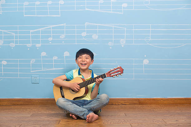 istock Asian six year old boy smiling with guitar in hand 181868200