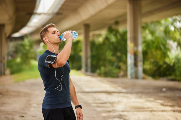 istock Male runner under bridge in the city drinking water 1818685487