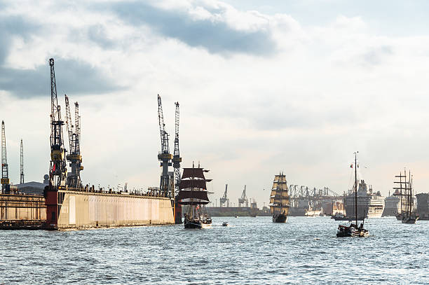 Some old sailing ship and modern cruise ships at the birthday parade of the harbor of Hamburg on the river Elbe in Germany. Warm sunset light in the evening with very nice clouds in the background. Copy space on the sky. All logos are removed.