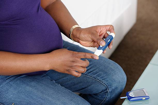 primer plano de mujer embarazada afroamericana el control de la glucosa en sangre - diabetes blood sugar test medical test healthcare and medicine fotografías e imágenes de stock