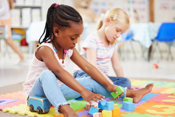 istock Education, kindergarten and children with toys for playing, child development and creative learning. School, youth and young girls with building blocks for fun, relax and educational games on floor 1818697674