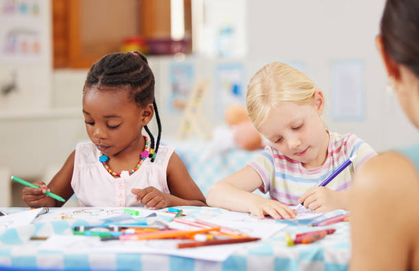 istock Children, pencil and drawing for homework in classroom with creative, art or project for picture. Little girl, friend and diversity with serious look for learning, education and decision for coloring 1818697715