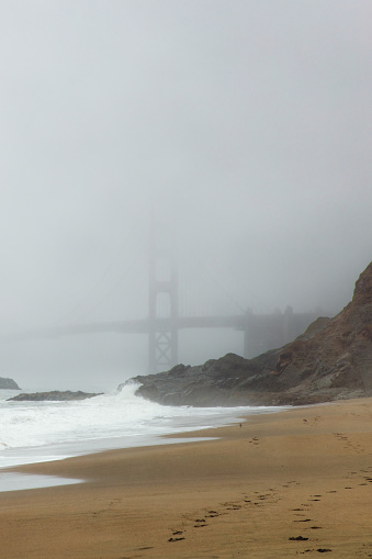 Dramatic view of tranquil scene at the beautiful central sand beach with red bridge covered by spring mist in San Francisco city, California