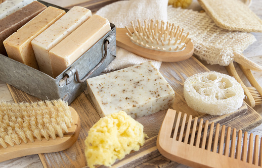 Organic handmade beige soap bars on soap saver bag near hygiene Items - natural sponges, brushes, bamboo toothbrushes and cotton swabs close up. Natural herbal products facecare