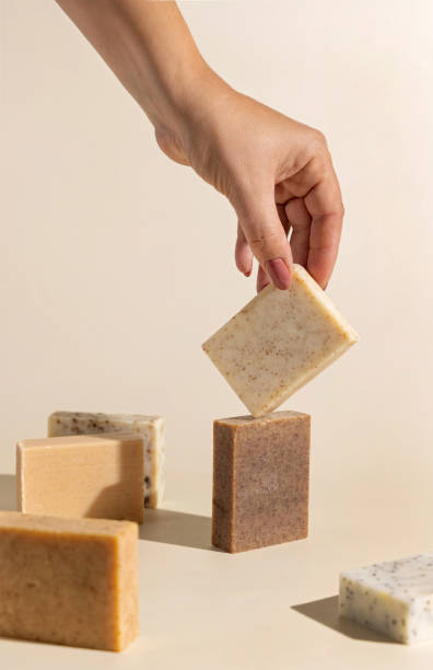 istock Hand keeps natural beige and brown soap bars on light beige, hard shadows 1818711623