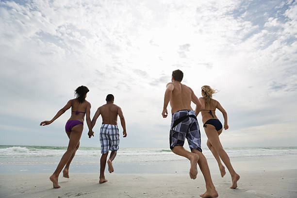 multi-etnici amici in esecuzione sulla spiaggia - men beach running shirtless foto e immagini stock