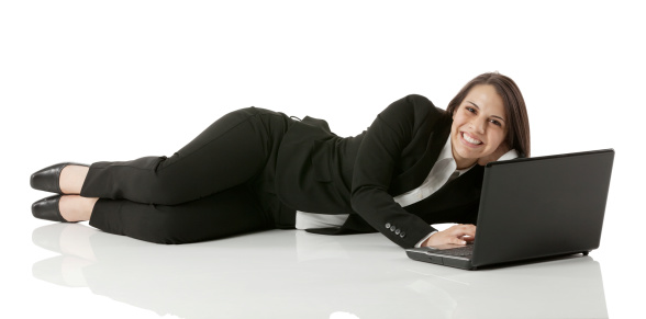 Smiling businesswoman lying on the floor with laptop