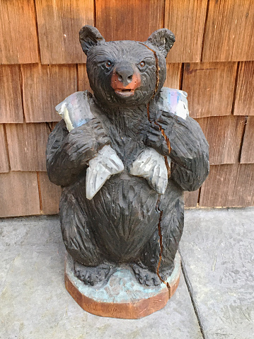 A wooden bear sculpture holding two fish over its shoulders on Vancouver Island, British Columbia, Canada.