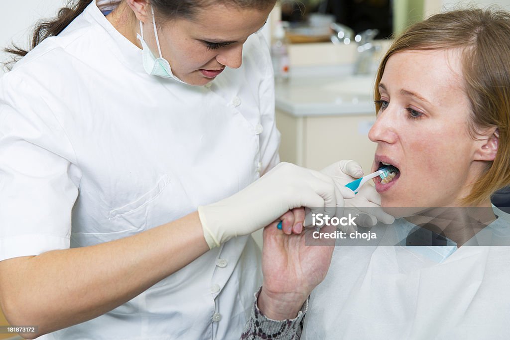 Oral hygiene...dental technician and woman patient Oral hygiene...dental technician is showin to a patient how to properly use tooth brush Adult Stock Photo
