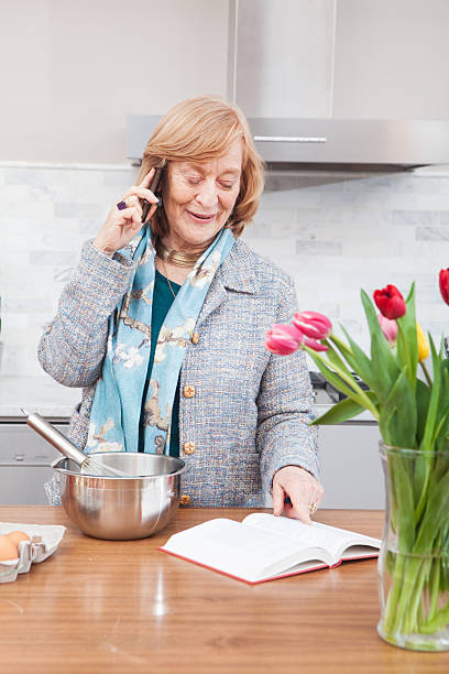 istock Happy grandmother on phone checking recepie in kitchen 181873339