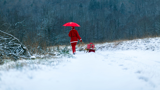 Santa Claus with red umbrella Walking Outdoors in Country land at Christmas Winter Time