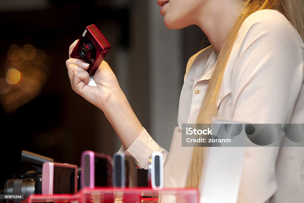 Shopping for digital camera Woman choosing digital camera in electronics storeNOTE:  All identifiable features from cameras are deleted Camera - Photographic Equipment Stock Photo