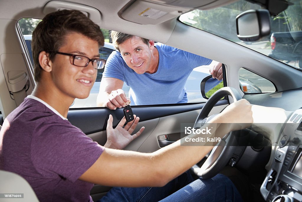 Father handing son car keys Father (40s) giving teenage son (15 years) car keys.  Focus on father. Parent Stock Photo