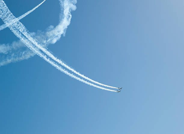 Aerobatic stunt show on the sky "Stunt show with aerobatic biplanes, smoke on blue sky" stunt airplane airshow air vehicle stock pictures, royalty-free photos & images