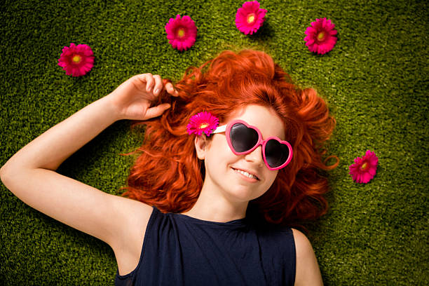 istock Redhaired girl with sunglasses lying on grass in park 181875111
