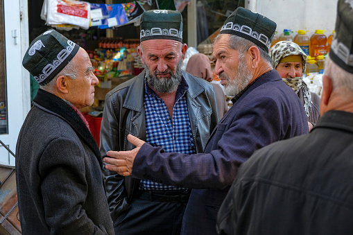 Istaravshan, Tajikistan - November 26, 2023: Men chatting at the Istaravshan Central Market, Tajikistan.