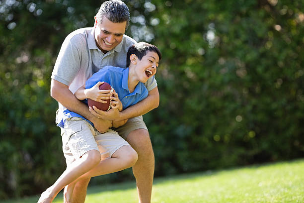 istock Father Carrying Son While Playing American Football 181875364
