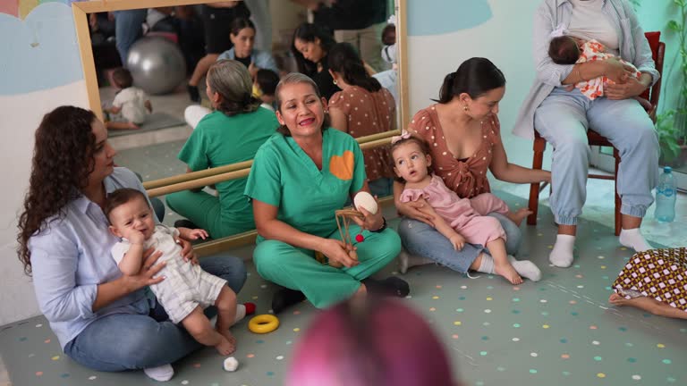 Mature woman teaching mothers how to breastfeed their babies at support group