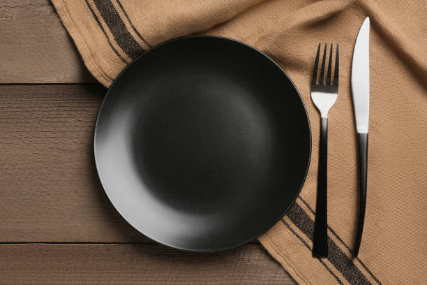 istock Clean plate and shiny silver cutlery on wooden table, flat lay 1818756693