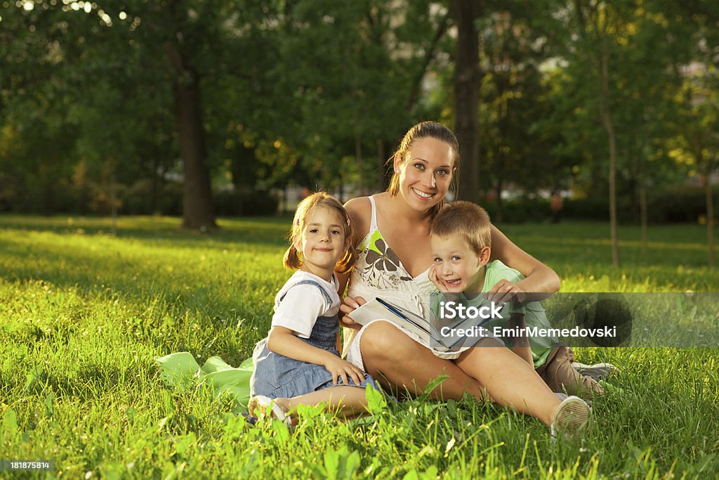 Madre con figlia e figlio leggere un libro aperto - Foto stock royalty-free di 6-7 anni