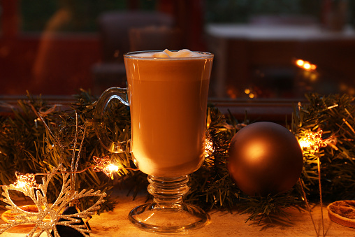 Glass of delicious hot cocoa and Christmas decoration on windowsill