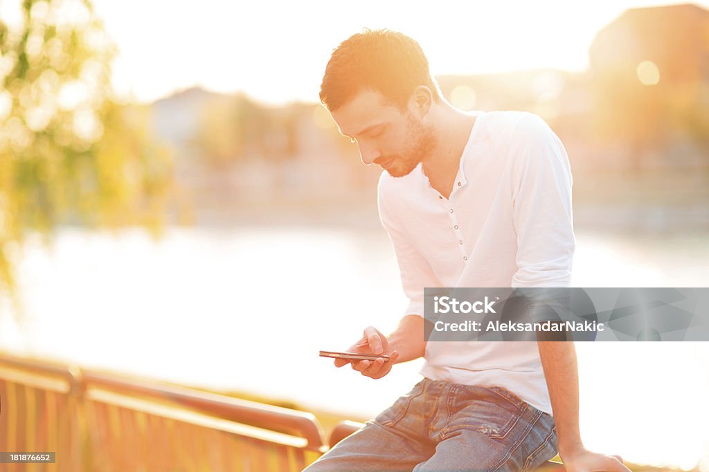 Young man using a smart phone outdoors Lifestyle portrait of a young man using a smart phone outdoors 20-29 Years Stock Photo