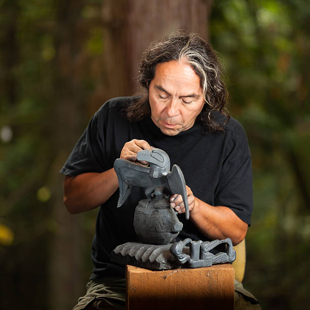 Mature man creating Haida carvings in a forest First Nations - Haida - carver working on argillite stone sculpture.   aboriginal art stock pictures, royalty-free photos & images
