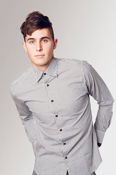 Trendy male portrait Attractive casual young man looking at camera in front of neutral background. High key. teenager boy haircuts stock pictures, royalty-free photos & images