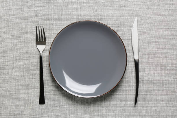 istock Clean plate and shiny silver cutlery on grey tablecloth, flat lay 1818774530