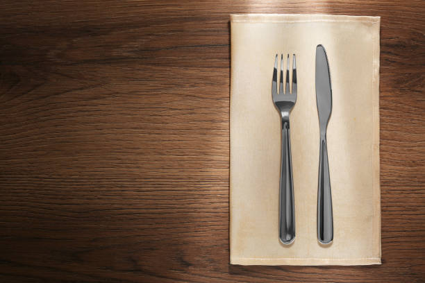 istock Shiny fork, knife and napkin on wooden table, top view. Space for text 1818776663