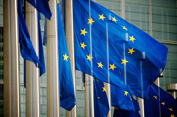 ес флагами, летящий на европейской комиссии здание, брюссель, бельгия - флаг европейского союза стоковые фото и изображения