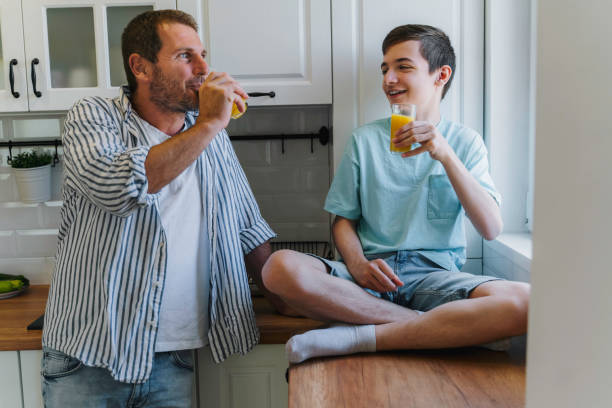 istock Father talking to his teenage son while drinking juice in the kitchen. 1818779863