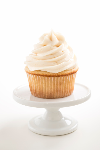 A vanilla cupcake on a white pedestal stand against a white background. (NOT ISOLATED)