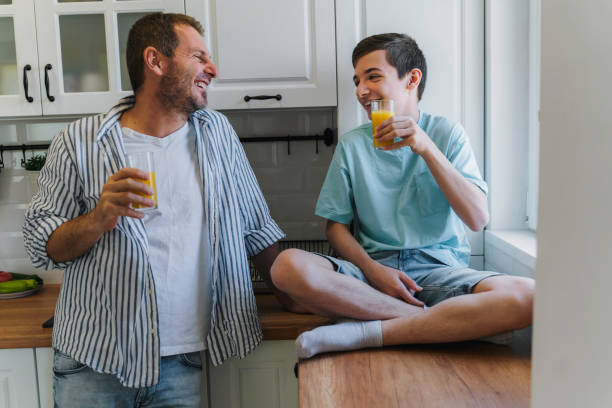 istock Father talking to his teenage son while drinking juice in the kitchen. 1818779998
