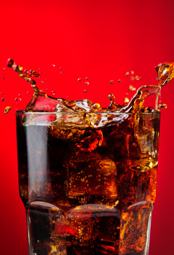 glass of cold cola soft drink with ice on wooden background