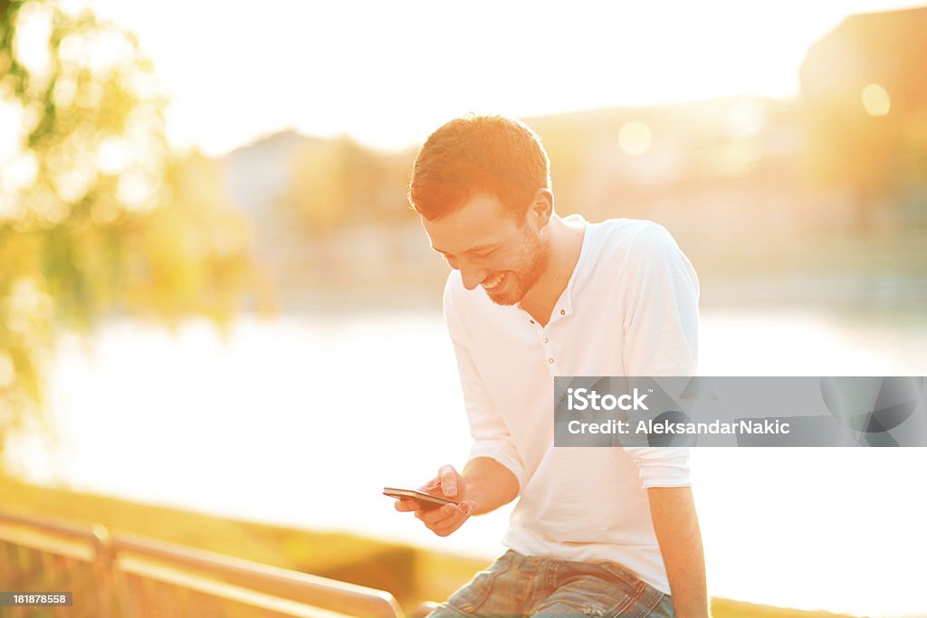 Uśmiechającego się człowieka za pomocą Inteligentny telefon na zewnątrz - Zbiór zdjęć royalty-free (20-29 lat)
