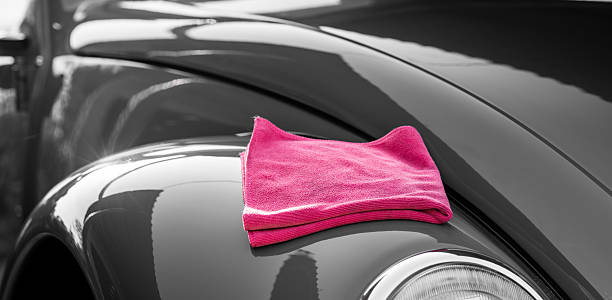 Shiny and clean black car with a pink rag on top Car wash. isolated color stock pictures, royalty-free photos & images