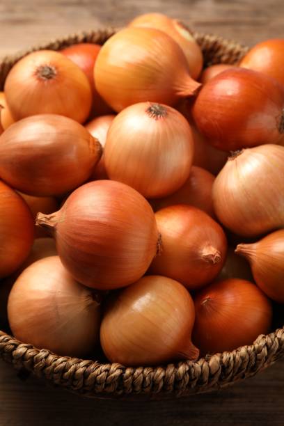 istock Wicker basket with many ripe onions on table, closeup 1818789051