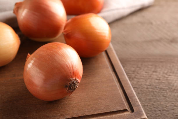 istock Many ripe onions on wooden table, closeup. Space for text 1818789567