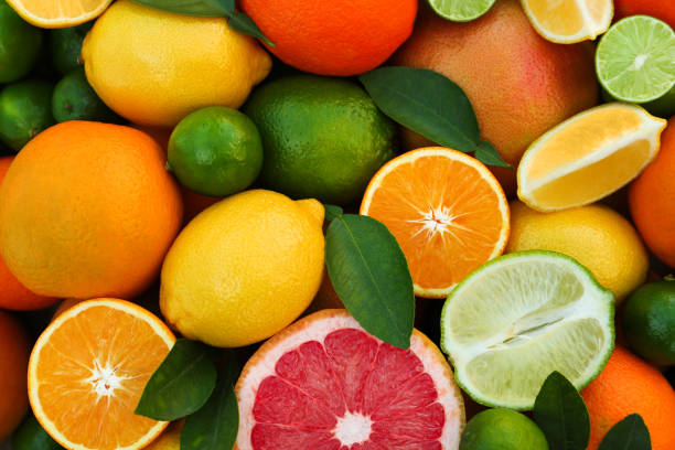 istock Different fresh citrus fruits and leaves as background, top view. 1818789593