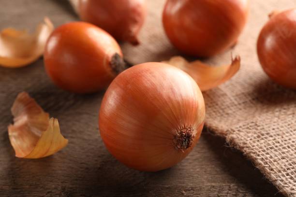 istock Many ripe onions on wooden table, closeup 1818789604