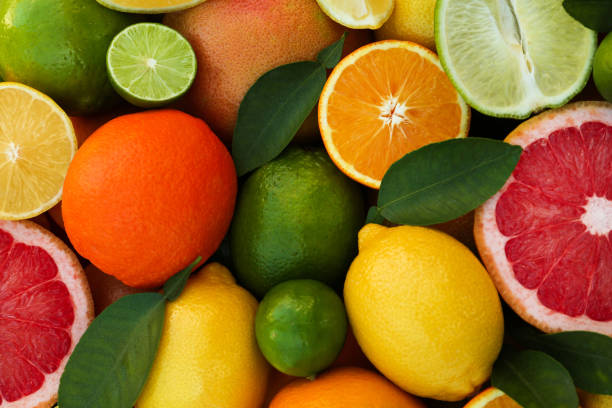 istock Different fresh citrus fruits and leaves as background, top view. 1818790112