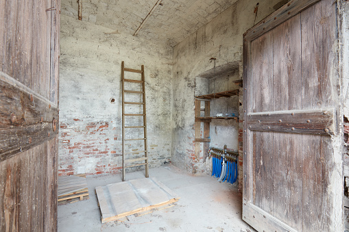 Old depository room with wooden portal in old country house in Italy