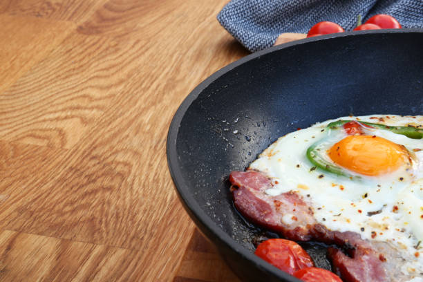 istock Delicious fried egg with bacon, tomatoes and pepper served on wooden table, closeup. Space for text 1818803812