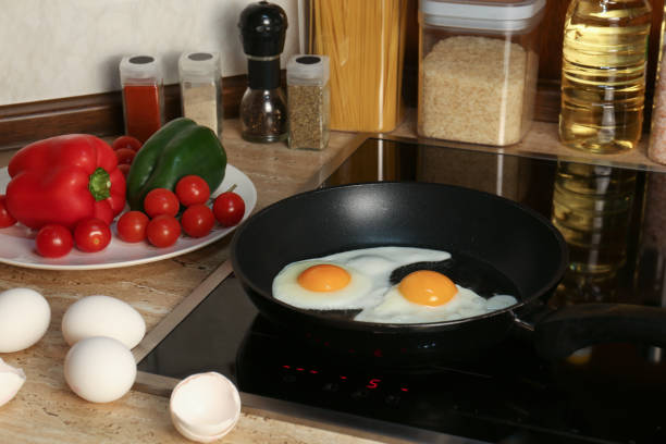 Cooking eggs for breakfast in frying pan on cooktop