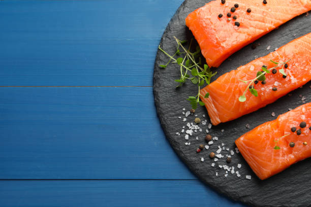 istock Fresh raw salmon and spices on blue wooden table, top view. Space for text 1818805467