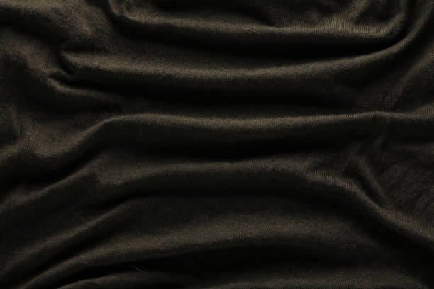 Close up abstract textile background of dark brown folded pleats of fabric, elevated top view, directly above